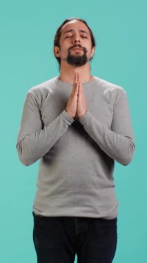 Dikey video dindar adam tanrısına dua ediyor, af diliyor. İbadet eden, el kol hareketi yapan, itiraf eden, af dileyen, stüdyo arka planında izole edilmiş, kamera A
