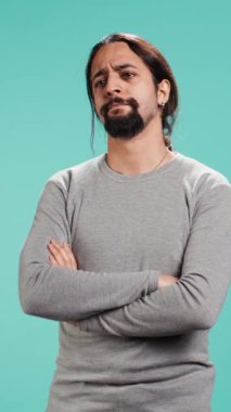 Dikey Videocu başını sallıyor, negatif duygu gösteriyor, tatmin olmadığını gösteriyor, stüdyo arka planında izole edilmiş. Sohbet sırasında arkadaşınla fikir ayrılığına düşen sinirli kişi, stüdyo arkaplanı