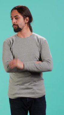 Boynunu parmaklarıyla kaşıyan bir adamın dikey video görüntüsü alışık olmadığımız sesleri dinliyor, kaynağını bulmaya odaklanıyor. Başını eğen kişi, tanımlayıcı gürültü odaklı, stüdyo arka planı