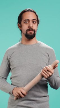 Çarpışma sırasında düşmana saldıran tehditkar adamın dikey videosu. Öfkeyle dolu hayalet bir Arap, göz korkutucu bir eş, silah taşıyor, stüdyo arka planında izole edilmiş, kamera B