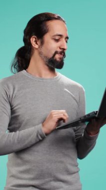 Dikey Videocu şirket için iş ile ilgili işler yapmak için dizüstü bilgisayar kullanıyor, stüdyo arka planında izole edilmiş. Ofis görevlisi, defter, kamera B 'de bütçe tahmini ve mali analiz yapıyor.