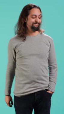 Dikey videoda gülümseyen adam arkadaşlarıyla selamlaşıyor, onları gördüğüne seviniyor, mavi stüdyo arka planında soyutlanmış. Dost canlısı el sallayan, dostça selamlaşan arkadaşlar, stüdyo arka planı, kamera A