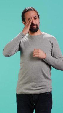 Dikey videocu kendini çok çalışmaktan ve uykusuzluktan yorgun hissediyor, gözlerini ovuşturuyor ve esniyor, stüdyo arka planında soyutlanıyor. Yorgun insan kendini uykulu hissediyor, yorgun olmak, stüdyo arkaplanı, kamera.