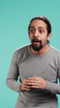 Şaşkın bakışlı bir adamın dikey video portresi. Gördüklerinden büyülenmiş. Stüdyo arka planında izole edilmiş. Heyecanlı, meraklı, hayranlık duyan, gözlerine inanamayan biri.