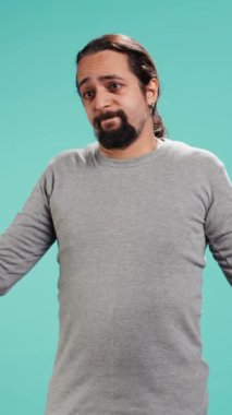Dikey videocu omuz silkiyor, belirsizlik ve çaresizliği ifade ediyor, yüz ifadesi sorunlu. Arkadaşına yardım edemeyen, güçsüz hisseden, stüdyo geçmişi olan biri.