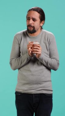 Dikey Videocu, mavi stüdyo arka planında izole edilmiş lezzetli kahveyi tadarken ve tadını çıkarırken gözlerini kapatır. İnsanlar enerji kazanmak ve üretkenlik yapabilmek için kafeinli içecekler içerler.