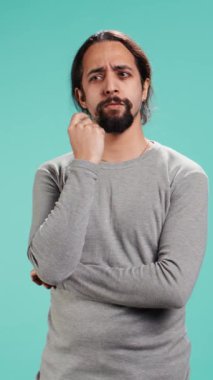 Dikey video dalgın adam derin düşüncelere dalmış, el hareketi yapıyor, stüdyo arka planında izole edilmiş. Emin olmayan kişi çene hareketi yapıyor, düşünüyor, stüdyo arkaplanı, kamera B