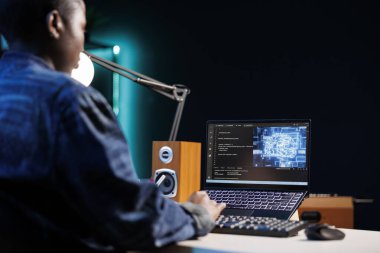 Profesyonel kadın müteahhit masadaki sinirsel ağı yönetiyor, dizüstü bilgisayardaki kodla çalışıyor. Siber güvenliği geliştiren, güvenli veri tabanı oluşturan Afrikalı Amerikalı serbest çalışanın omzunun üstünden..