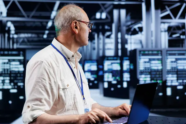 stock image Proficient supervisor using laptop, setting up high bandwidth dedicated multiplayer gaming servers in supercomputer hub to accommodate more traffic from worldwide locations and avoid low ping