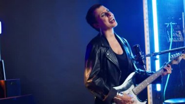 Vahşi rockçı kadın heavy metal konserinde bas gitar çalıp şarkı söylüyor, güçlü sesini ve isyankar enerjisini sergiliyor. Canlı yayında müzikal yetenek ve ikonik stil. Kamera A.