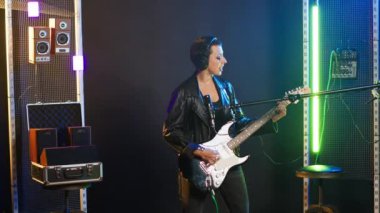 Deri ceketli, heavy metal çalan rock yıldızı kadın elektro gitarını enerjiyle parçalıyor. Grunge stili cesur asi müzisyen onun ikonik canlı performansını tanımlıyor. Kamera B.