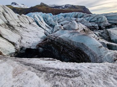 Buz, İzlanda 'daki Vatnajokull buzullarını büyük mavi buzullarla kaplamıştı. Karla kaplı Nordik tepeler, donmuş soğuk su, buz blokları ve gölü olan buzullu göl..