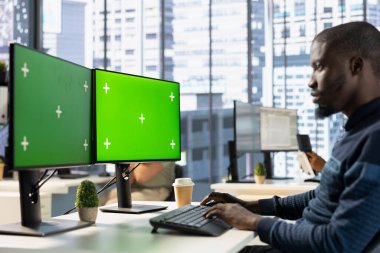 Adam bilgisayar ekranının detaylarını kontrol ediyor, görevleri çözüyor. Belgelerin yeşil ekran bilgisayar kullanılarak kalite güvence standartlarına uygun olduğundan emin olmak için görevdeki muhasebeci