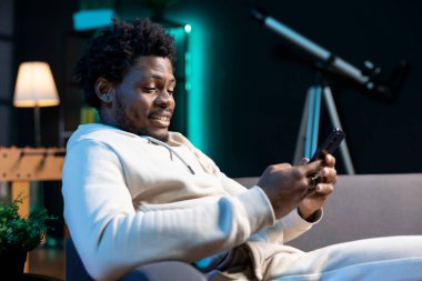 Adam mesajlar yazıyor, akıllı telefon klavyesine yazıyor, çevrimiçi arkadaşlarla sohbet ediyor. Evde sosyal medyada gezinen, komik mesajlara gülen, boş zamanların tadını çıkaran kişi