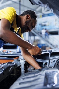 Araba servisindeki tamirci bozuk motoru tamir etmek için profesyonel mekanik alet kullanıyor. Garajda çalışan, müşteri otomobilini tamir eden, optimal otomotiv performansı sağlayan yetenekli bir işçi.