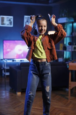 Sosyal medya platformunda büyüleyici dans gösterisi yapan neşeli çocuk çevrimiçi mücadeleye katılıyor. Neşeli genç, internet izleyicileri için ev stüdyosunda video çekiyor.