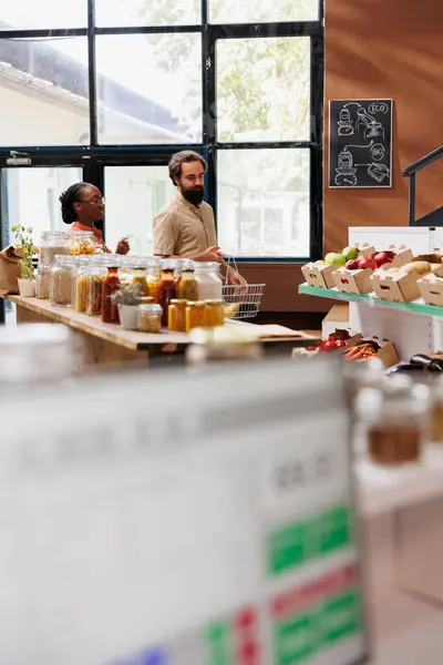 stock image Health driven multiracial couple enter eco friendly convenience store to shop for freshly harvested produce. Black woman and caucasian man looking around local bio food supermarket.