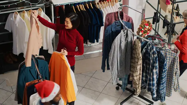 Noel Baba şapkası takan çalışanlar ve Noel süslü giyim mağazalarında gezen müşteriler. Xmas 'taki işçiler ve müşteriler moda dükkanını süslüyor