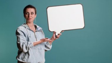 Moda tarzı olan bir kadın model stüdyoda bir konuşma balonu tutuyor, boş bir reklam panosu ikonu olan bir reklam filmi yaratıyor. Havalı sinirli kadın reklam tabelası sunuyor. Kamera B.