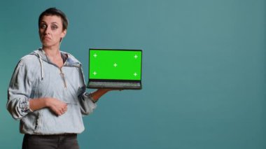 Genç yetişkinler, modern teknolojiyi kablosuz aygıtlarda kullanarak stüdyoda izole edilmiş krom ekranlı dizüstü bilgisayarı işaret ediyorlar. Kendine güvenen bir kadın reklam yapıyor. Kamera B.