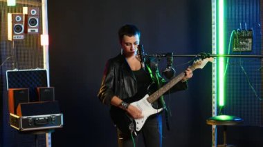 Rock star woman in a leather jacket playing an electric guitar in studio, rocking out to powerful music in a live performance. Fierce artist entertainer creating wild rebellious atmosphere. Camera B.