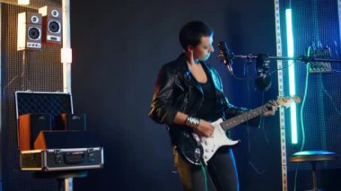 Rock star woman in a leather jacket playing an electric guitar in studio, rocking out to powerful music in a live performance. Fierce artist entertainer creating wild rebellious atmosphere. Camera A.