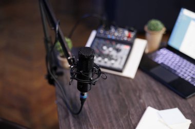 Mikrofon, dizüstü bilgisayar ve ses ekipmanlarının yer aldığı bir radyo programı veya podcast için ev kayıt kurulumu. Profesyonel mikrofon ve ses mikseri içeren en iyi masa görüntüsü, ev stüdyosu için ideal.