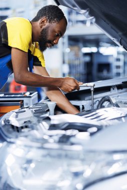Araba servisindeki tamirci bozuk ışık sistemini tamir etmek için profesyonel mekanik alet kullanıyor. Garajdaki çalışkan işçi müşteri otomobili tamiri, optimal otomotiv performansı sağlama