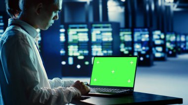 Çalışan, farklı iş yükleri için işlem kaynakları sağlayan veri merkezi donanım kümelerini onarmak için yeşil ekran dizüstü bilgisayar kullanıyor. Bıçak sunucularını onarmak için kullanılan düzenek tarafından desteklenen mühendis