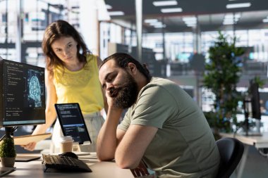 Programcı, karmaşık problemleri çözen yapay zeka öğrenme API 'leri geliştirirken yönetici tarafından masada uyurken yakalandı. Yorgun uyuyan adam, öngörü modelleri çalışırken takım lideri tarafından uyandırıldı.