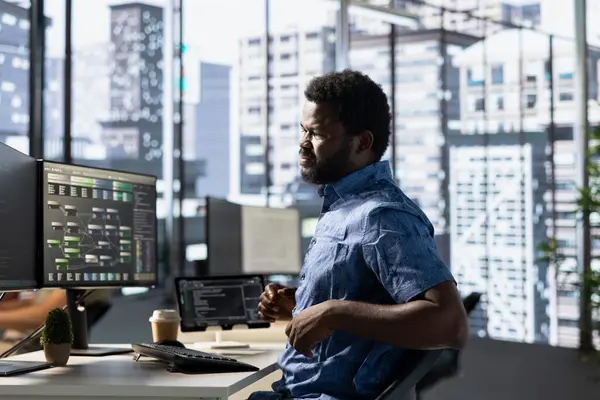 stock image Programmer in pain, suffering muscle sprain while developing machine learning APIs solving complex problems. Man feeling backache from sitting on desk chair while training predictive models