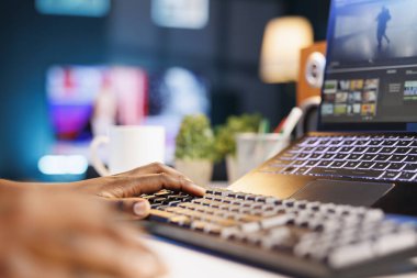 Siyah kişi dizüstü bilgisayarını ve klavyesini kullanarak dijital içeriği kurguluyor ve yaratıyor. Afrikalı Amerikalı yapımcı kişisel bir bilgisayarda çoklu görev ve kurgu yazılımı kullanıyor.