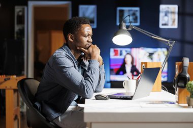 Stresli bir çalışan, evden yöneticilik sorumluluklarını çözmeye çalışıyor, geceleri uzaktan kumanda yapıyor. Afrika kökenli Amerikalı işçiler kalkınmaya yardımcı olmak için yönetim stratejisi okuyorlar.