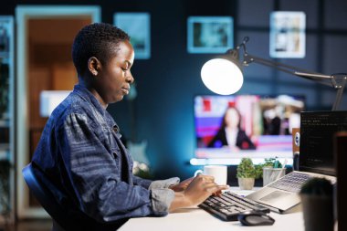 Dizüstü bilgisayarda çalışan, verileri yöneten, programlayan ve siber güvenliği sağlayan Afrikalı Amerikalı serbest çalışan bir kadın. Genç siyahi kadın dijital cihaz kullanarak kod ve ağ sistemi kullanıyor..