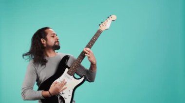 Elektro gitarla rock müzik çalan yetenekli biri, stüdyo arkaplanından izole edilmiş. Müzisyen müzik aleti kullanıyor, konser yaparken eğleniyor, eğlenceli şarkılar yapıyor, kamera B