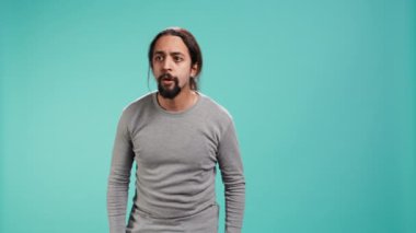 Yüzünü ellerle örten korkmuş bir adamın portresi stüdyo arka planında izole bir şekilde duruyor. Korkmuş yüz ifadesi olan korkmuş kişi şoka uğruyor, perişan hissediyor, kamera B