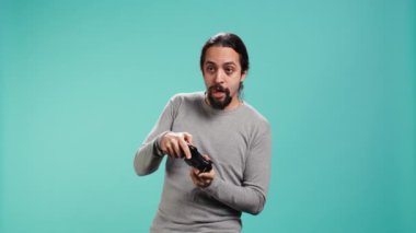 Oyunu ekrandan izledikten sonra hayal kırıklığına uğramış yüz ifadesi olan oyuncu, kumandayı elinde tutuyor. Adam video oyunu kaybettikten sonra üzgün, oyun sahası ile oynuyor, stüdyo arka planında izole edilmiş, kamera B