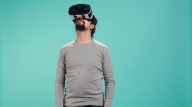 Sanal gerçeklik gözlüğü takan heyecanlı teknoloji hayranı etrafa bakıyor. Arap adam ileri teknoloji modern VR gözlükleri kullanıyor, dokunaklı hareketler yapıyor, stüdyo arka planı, kamera B