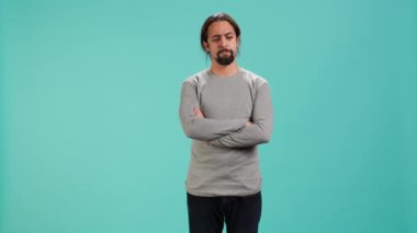 Huysuz adam kollarını kavuşturuyor, olaylardan dolayı üzgün, stüdyo arka planında izole edilmiş. Stresli, huysuz, başını sallayan, rahatsız edici haberlerle nutku tutulmuş, kamera A
