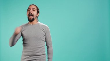 Favori spor takımı için tezahürat yaparken yumruğunu sallayan bir adam stüdyo arka planında izole edilmiş. Yoğun bir coşku ifadesi ve tutku gösteren kişi, oyun sırasında yardımcı takım, kamera B