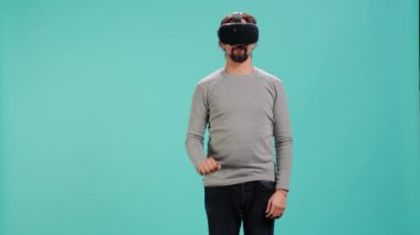 Teknoloji meraklısı sanal gerçeklik gözlüğü takıyor, jestler yapıyor. Arap adam ileri teknoloji modern VR gözlükleri kullanıyor, dokunaklı hareketler yapıyor, stüdyo arka planı, kamera A