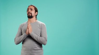 Bir adamın portresi dilenmek için el ele tutuşuyor, dilek tutuyor, stüdyo arka planında izole edilmiş iyi haberler umuyor. Sonuçları bekleyen, olumlu sonuç için dua eden kişi, kamera B