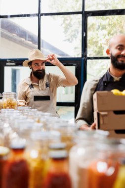 Local farmer provides organic items to happy vendor who serves eco conscious customers in zero-waste store. Young man delivers crates full of freshly harvested, nutritious produce to retailer. clipart