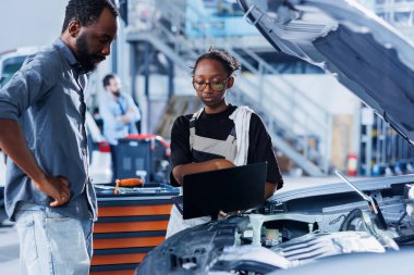 Araba servisindeki teknisyen bozuk otomobil motorunu tamir ettikten sonra faturayı hesaplamak için dizüstü bilgisayar kullanır. Çalışkan garaj çalışanı, aracı tamir ettikten sonra müşteriyi son maliyetler hakkında bilgilendirmek için aygıt kullanır