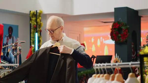 stock image Senior man browsing shirts in festive clothing store during winter Christmas holiday season, looking at trendy seasonal clothes, doing retail therapy looking for shopping advice