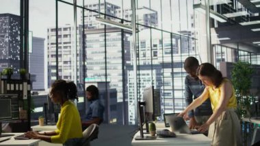 İşçilerle birlikte dizüstü bilgisayara bakıp bitirilmiş projeyi kontrol eden Afrikalı Amerikalı bir yönetici. Şirket yöneticisi ve kadın not defteri, kamera B 'deki verileri analiz ediyorlar.