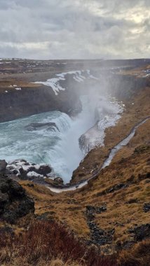 İzlanda bölgesinde güzel bir Gullfoss şelalesi, kışın doğal hava şartları altında büyük bir nehir akıntısı. Karla kaplı kuzey manzarası tepeler ve düşen dondurucu soğuk su, inanılmaz şelale.