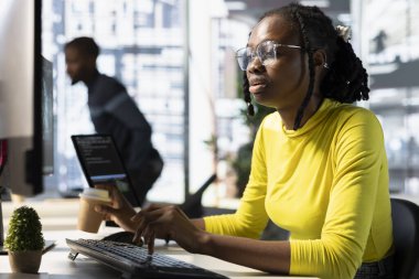 Ofis memuru bilgisayar monitörüne bakıyor, iş görüşleri bulmak ve projeyi bitirmek için gerekli anahtar verileri kontrol ediyor. Afrikalı Amerikalı kadın bilgisayardaki verileri analiz ediyor.