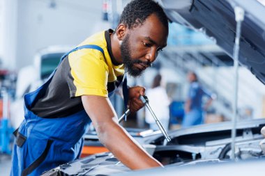 Araba servisindeki tamirci bozuk frenleri tamir etmek için profesyonel mekanik alet kullanıyor. Garajdaki yetkili işçiler müşteri otomobili tamiri, optimal otomotiv performansı garantisi