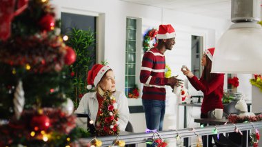 Tasasız iş arkadaşları süslemelere bakarak kahve molasının keyfini çıkarırken, Noel süslemeli ofis çalışanları geç kalmış projeler üzerinde çalışıyor. Şenlikli çalışma alanında stresli işçiler